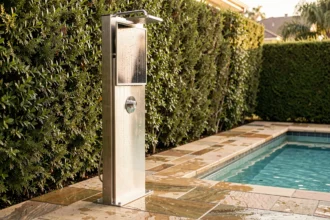 Douche solaire en inox installée au bord d'une piscine résidentielle avec carrelage en pierre naturelle