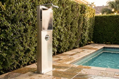 Douche solaire en inox installée au bord d'une piscine résidentielle avec carrelage en pierre naturelle