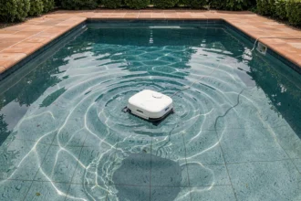 Robot nettoyeur de piscine automatique vu du dessus en train de nettoyer le fond d'un bassin résidentiel aux eaux claires
